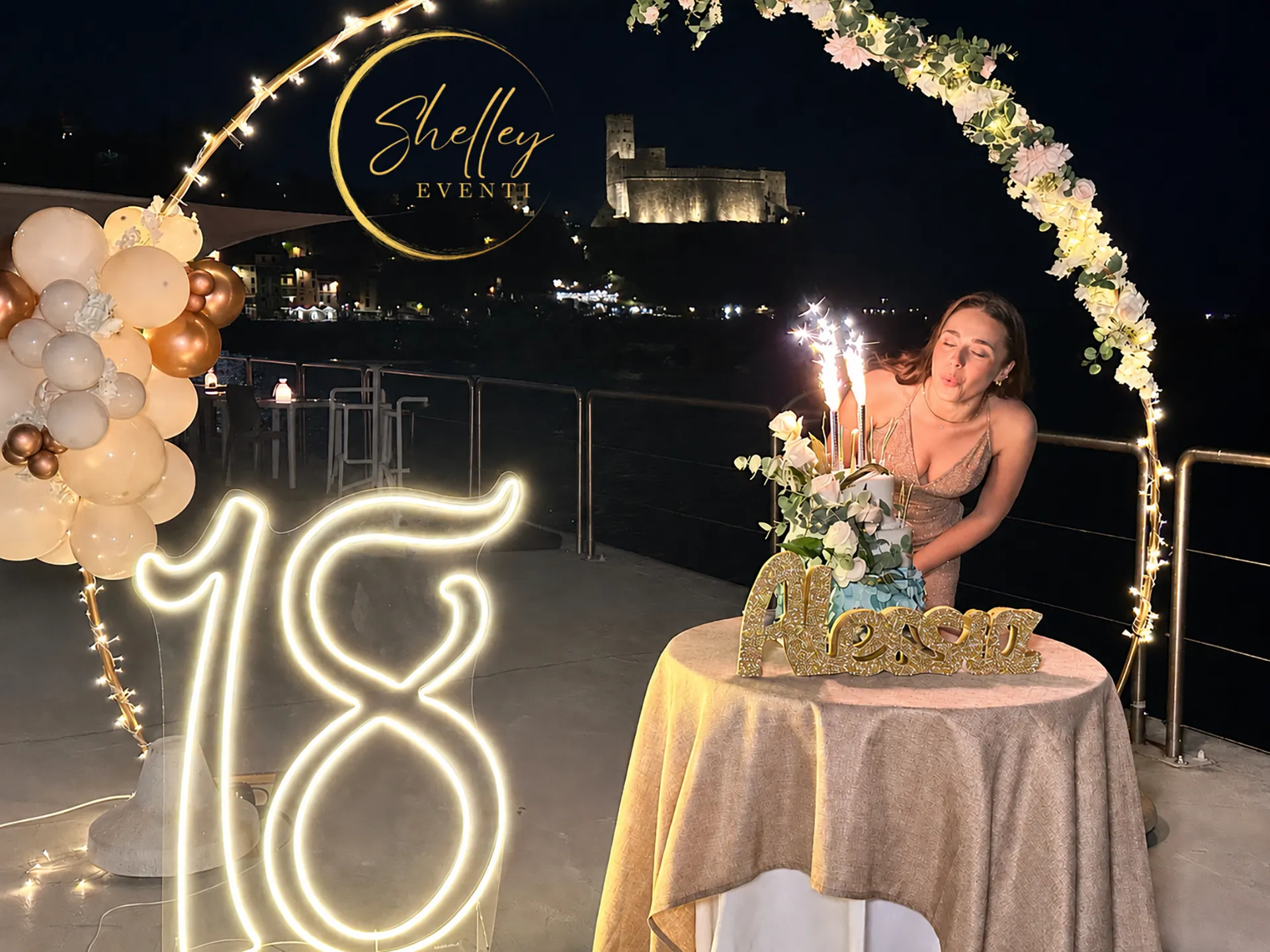 Nell'immagine, una ragazza sta spegnendo le candeline per festeggiare il suo diciottesimo compleanno presso la terrazza dell'Hotel Shelley e Delle Palme.