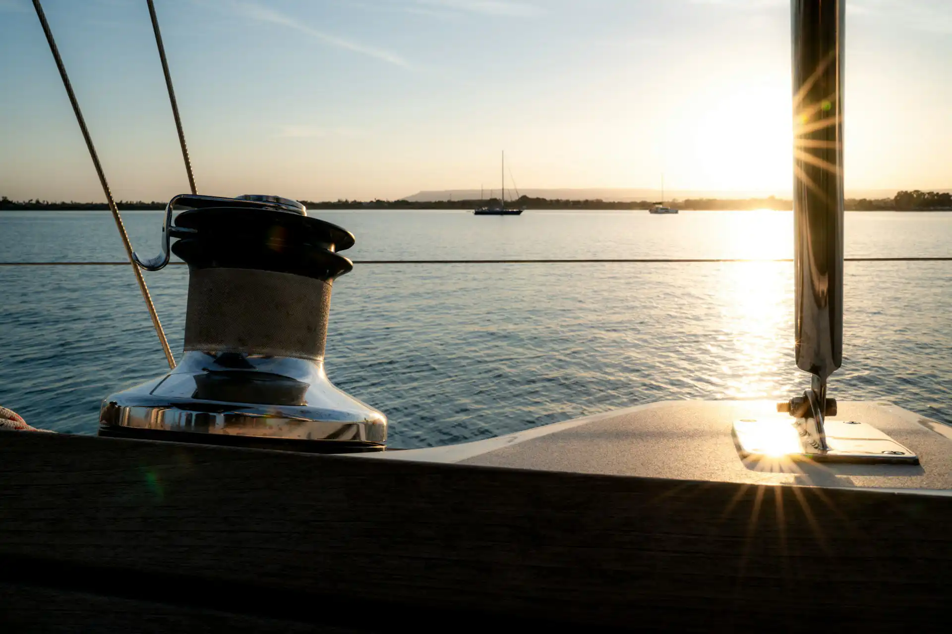 Nell'immagine, un primo piano della prua di una barca e, di fronte, il mare col sole al tramonto.