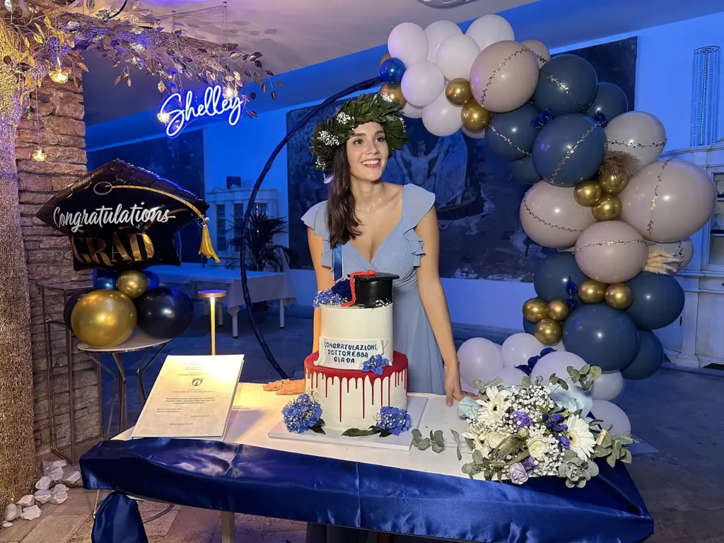 Nell'immagine, una ragazza davanti a una torta con la scritta "Congratulazioni dottoressa Giada" per la sua laurea.